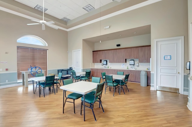 dining room featuring visible vents, light wood-type flooring, a towering ceiling, and a ceiling fan