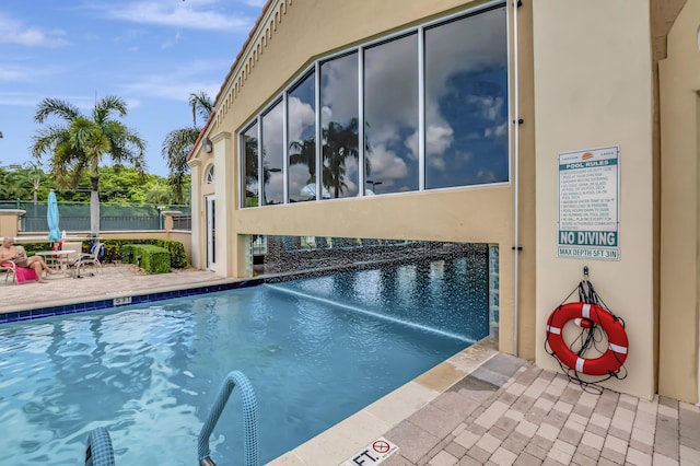 community pool with a patio and fence