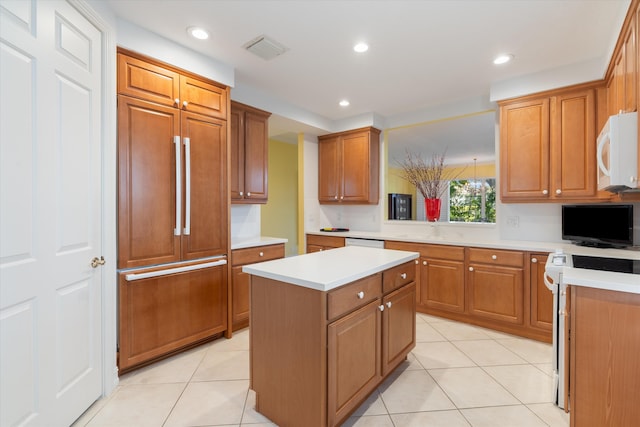 kitchen with light tile patterned floors, white appliances, a kitchen island, visible vents, and light countertops