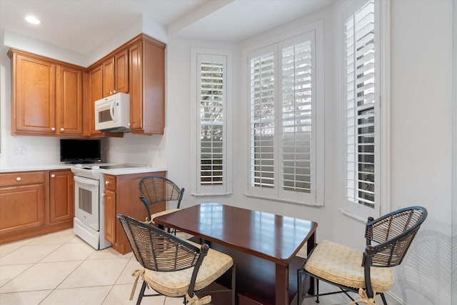 kitchen featuring brown cabinets, white appliances, light tile patterned floors, and light countertops