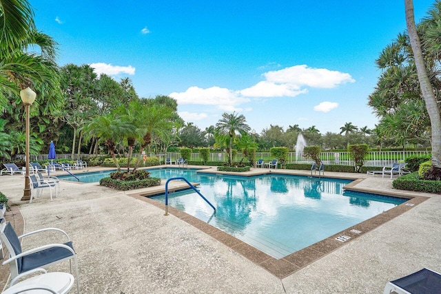 community pool with a patio area and fence