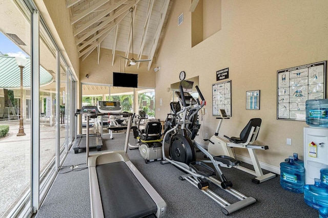 exercise room featuring high vaulted ceiling, baseboards, and visible vents