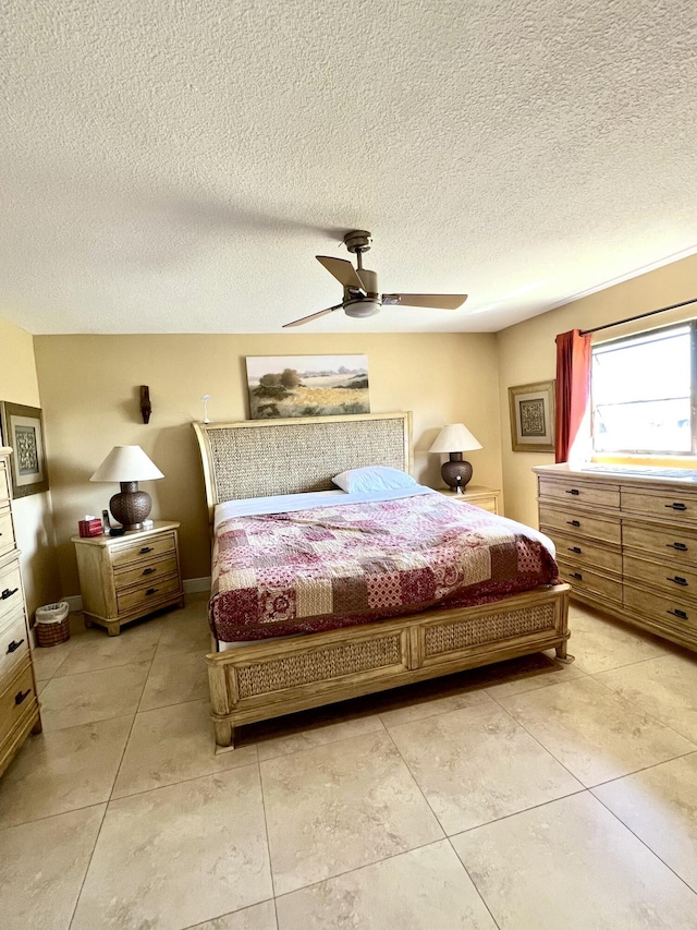 bedroom with a ceiling fan, light tile patterned flooring, and a textured ceiling