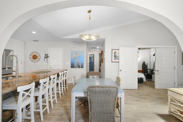 dining space with arched walkways, light wood finished floors, lofted ceiling, recessed lighting, and visible vents