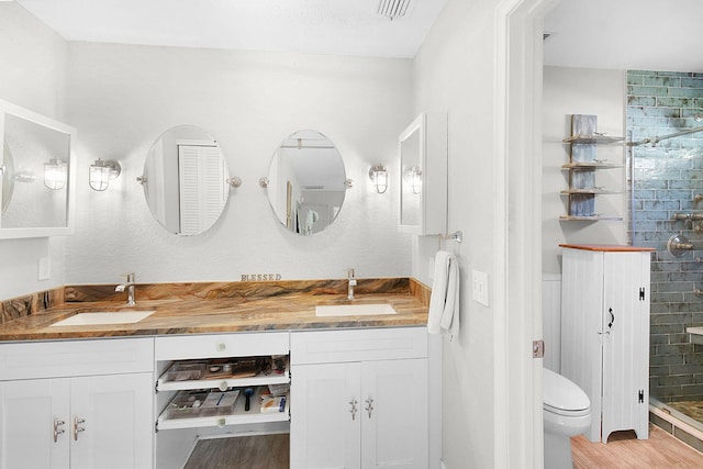 full bath with double vanity, a stall shower, a sink, and toilet