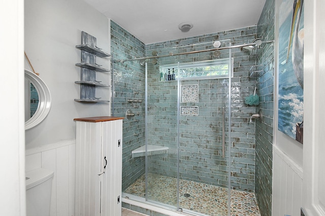 full bathroom featuring wainscoting, a shower stall, and toilet