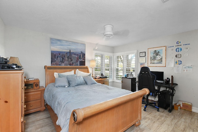 bedroom featuring baseboards, ceiling fan, light wood-style flooring, and a textured ceiling