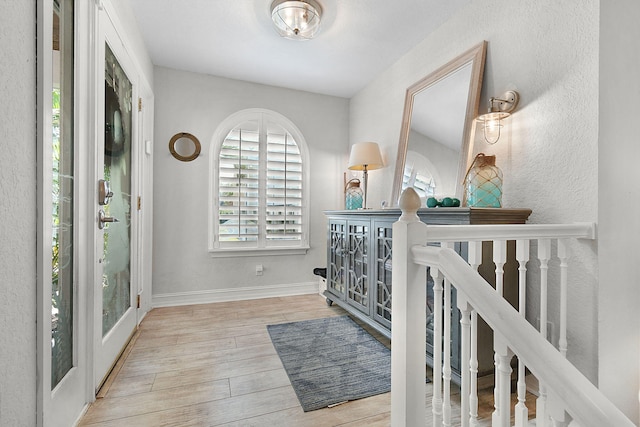 hall featuring light wood-style flooring and baseboards