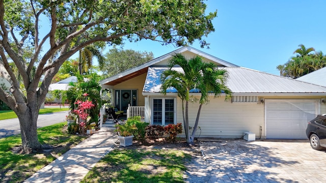 view of front facade with metal roof, a porch, decorative driveway, and an attached garage