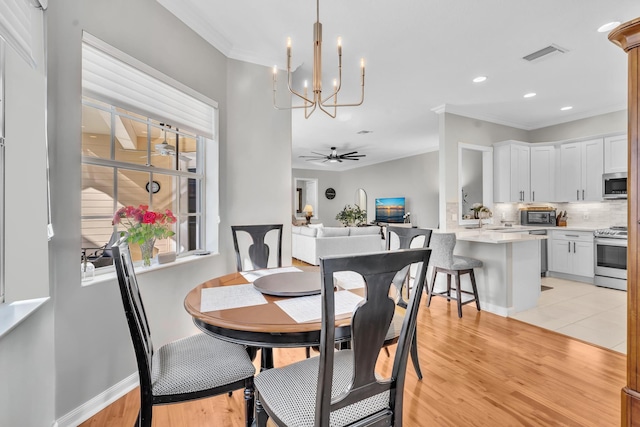 dining area featuring ceiling fan with notable chandelier, visible vents, baseboards, ornamental molding, and light wood-type flooring