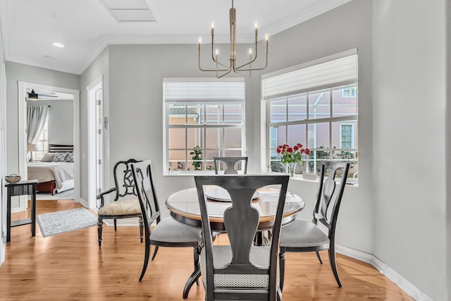 dining area featuring baseboards, crown molding, visible vents, and light wood finished floors