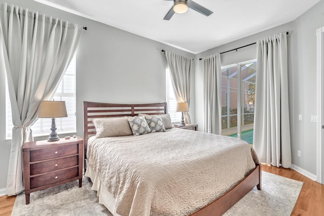 bedroom featuring baseboards, multiple windows, light wood-type flooring, and access to exterior