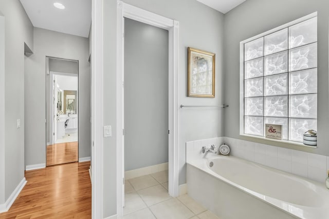 bathroom with a garden tub, baseboards, and tile patterned floors