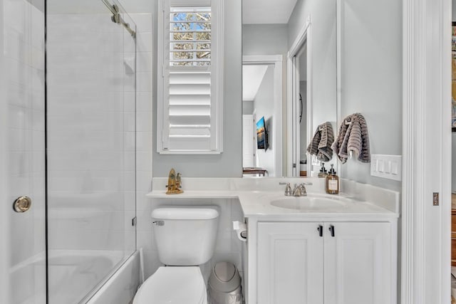 bathroom with shower / bath combination with glass door, vanity, and toilet