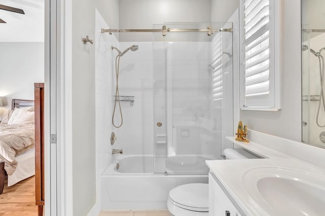 ensuite bathroom featuring connected bathroom, toilet, wood finished floors, combined bath / shower with glass door, and vanity