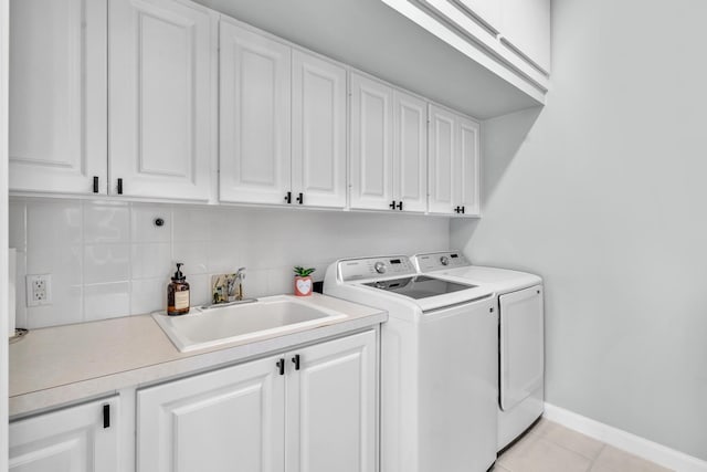 clothes washing area with cabinet space, light tile patterned floors, baseboards, washer and clothes dryer, and a sink