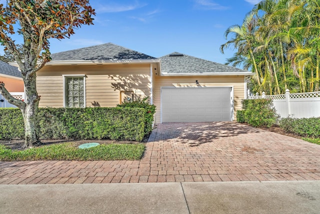 view of front of property featuring an attached garage, fence, decorative driveway, and roof with shingles