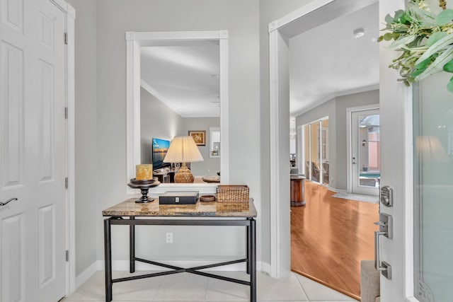 interior space featuring crown molding, baseboards, and light tile patterned floors