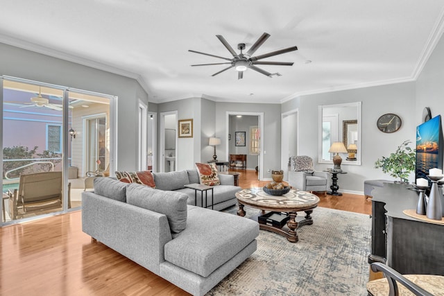 living room with a ceiling fan, light wood-type flooring, crown molding, and baseboards