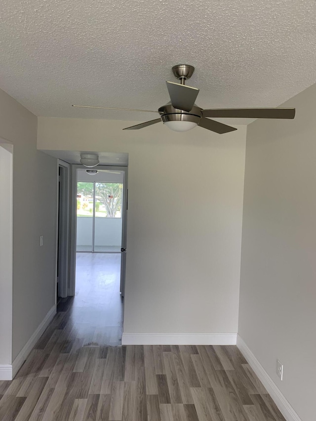 unfurnished room with a ceiling fan, a textured ceiling, baseboards, and wood finished floors