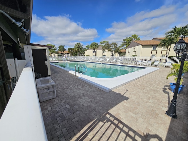 community pool featuring a residential view, a patio area, and fence