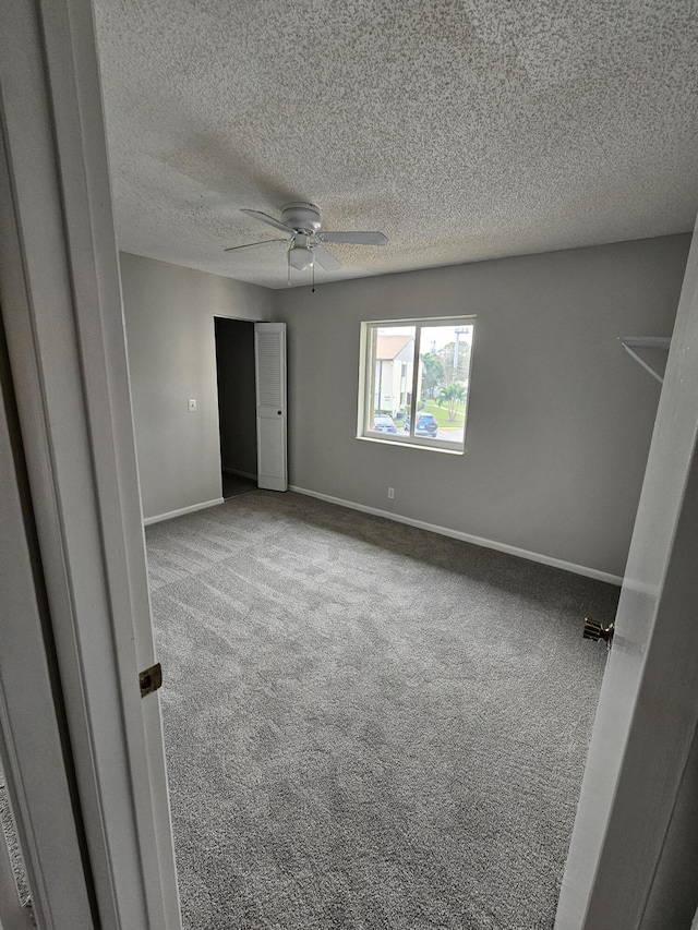 unfurnished bedroom featuring baseboards, carpet, ceiling fan, and a textured ceiling