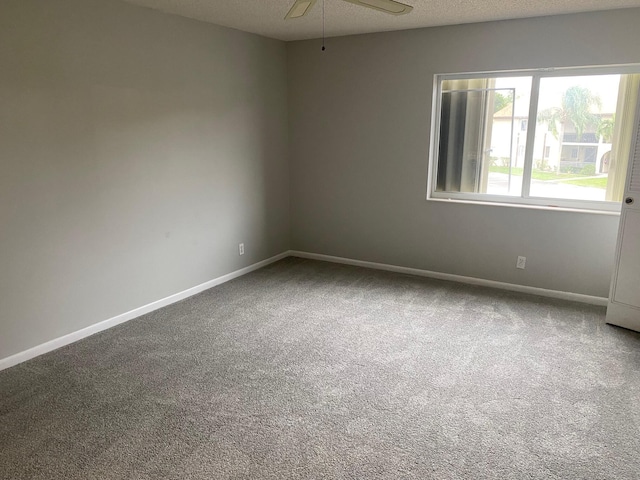 carpeted empty room with a textured ceiling, ceiling fan, and baseboards