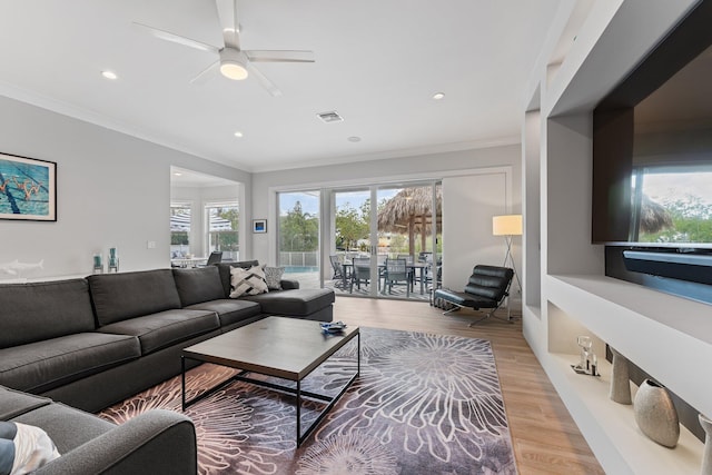 living area with visible vents, ornamental molding, recessed lighting, light wood-style flooring, and a ceiling fan