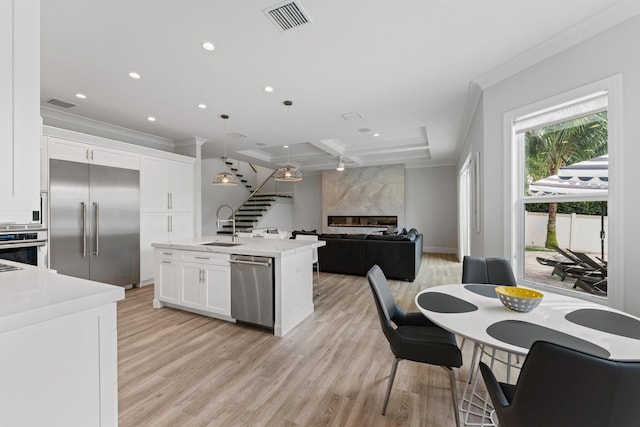 kitchen featuring visible vents, appliances with stainless steel finishes, a fireplace, and crown molding