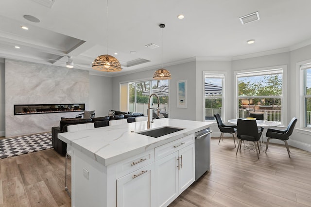 kitchen with visible vents, a sink, stainless steel dishwasher, light wood-style floors, and a fireplace