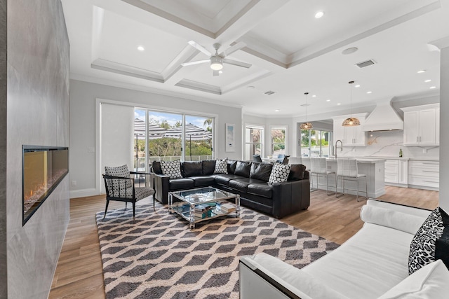 living area featuring light wood-type flooring, beam ceiling, ornamental molding, coffered ceiling, and recessed lighting