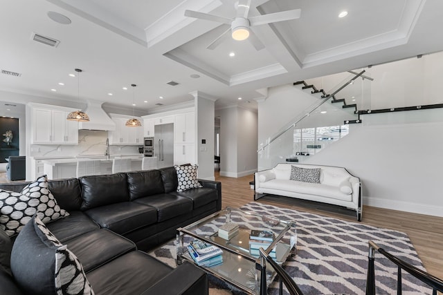 living area with light wood-type flooring, visible vents, and stairway