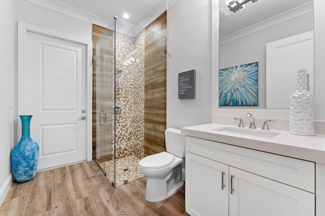 bathroom featuring a shower stall, vanity, toilet, and wood finished floors