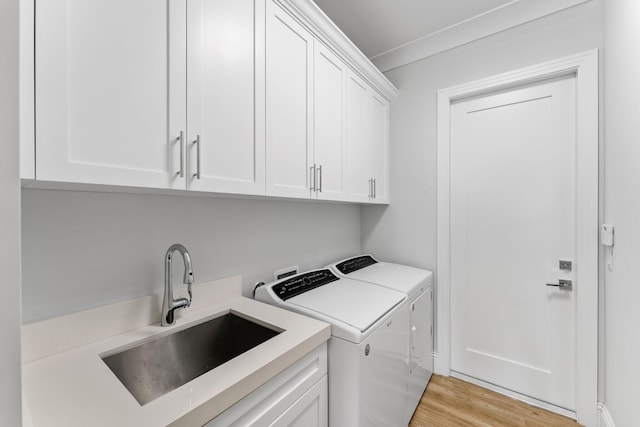 washroom with cabinet space, separate washer and dryer, light wood finished floors, and a sink