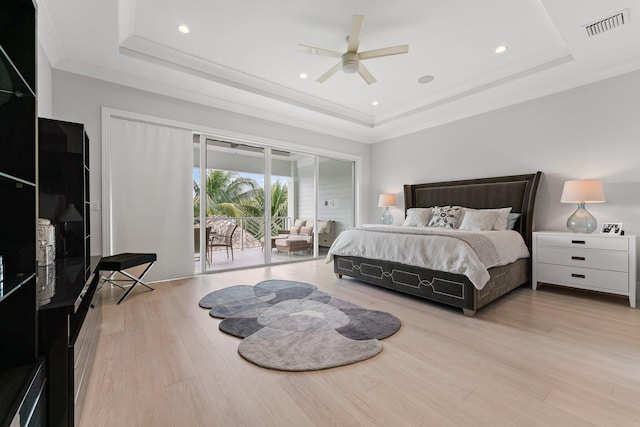 bedroom featuring visible vents, wood finished floors, a raised ceiling, and access to outside