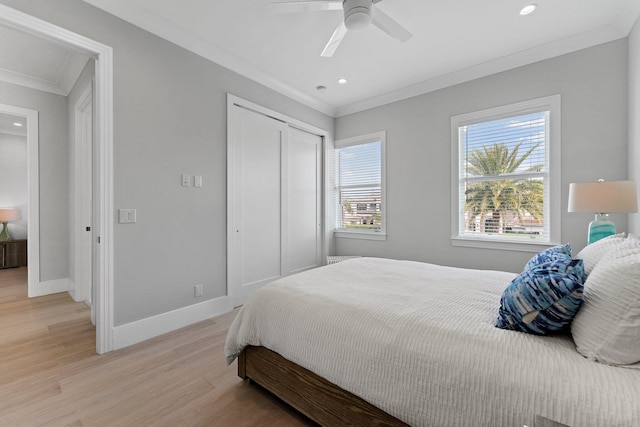 bedroom featuring crown molding, light wood-style flooring, baseboards, and a closet