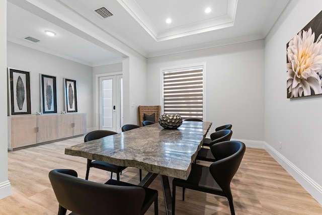 dining space featuring visible vents, baseboards, light wood-style flooring, and crown molding