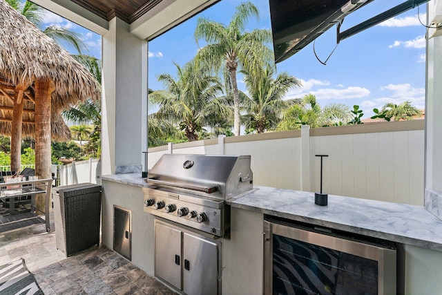 view of patio with fence, exterior kitchen, outdoor dining area, wine cooler, and a grill