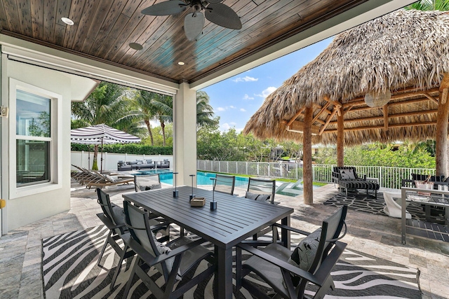 view of patio featuring outdoor dining space, fence, a fenced in pool, and a ceiling fan