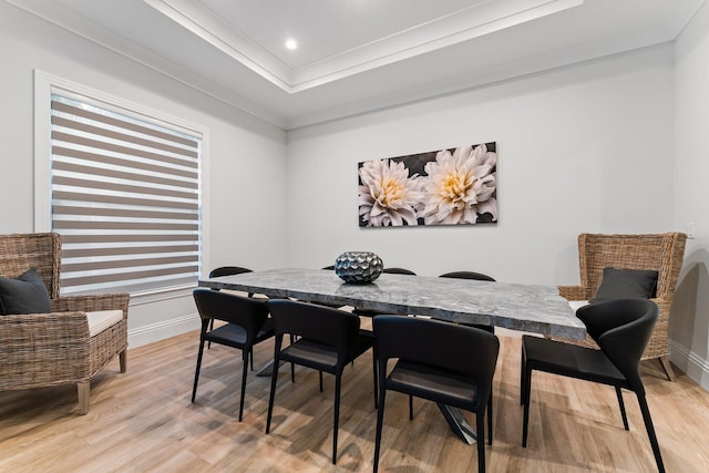 dining space featuring baseboards, light wood-style flooring, recessed lighting, ornamental molding, and a raised ceiling