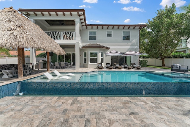 view of swimming pool featuring a patio area, a pool with connected hot tub, and fence