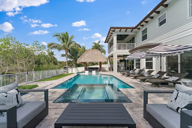 view of swimming pool with an outdoor living space, a pool with connected hot tub, a patio area, and a fenced backyard