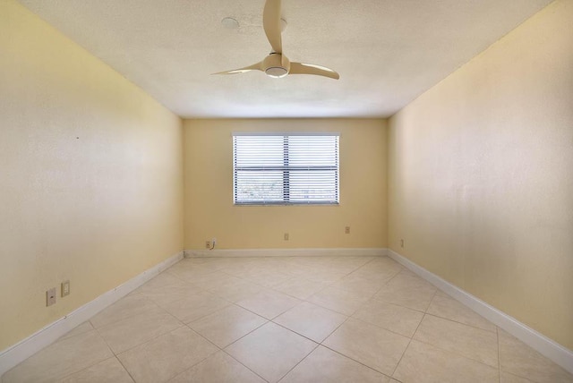 empty room featuring light tile patterned flooring, ceiling fan, a textured ceiling, and baseboards