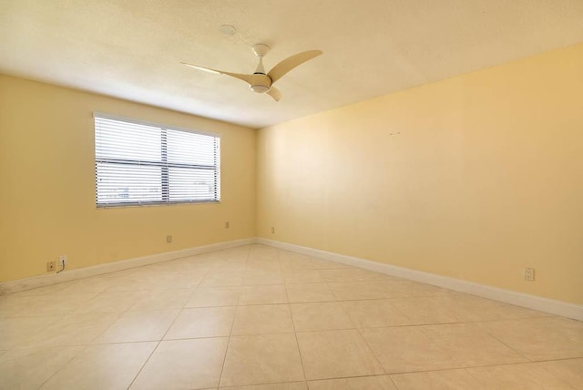 spare room featuring light tile patterned floors, ceiling fan, and baseboards