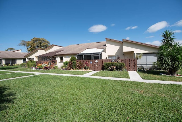 townhome / multi-family property with a front yard, fence, and stucco siding