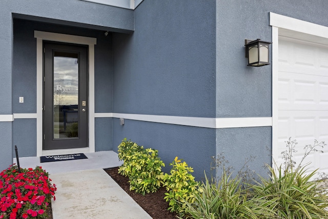 property entrance with a garage and stucco siding