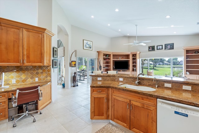 kitchen with stone counters, plenty of natural light, white dishwasher, and a sink