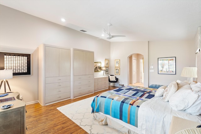 bedroom with arched walkways, ceiling fan, visible vents, vaulted ceiling, and light wood finished floors