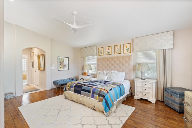 bedroom with arched walkways, ceiling fan, dark wood-style flooring, and vaulted ceiling