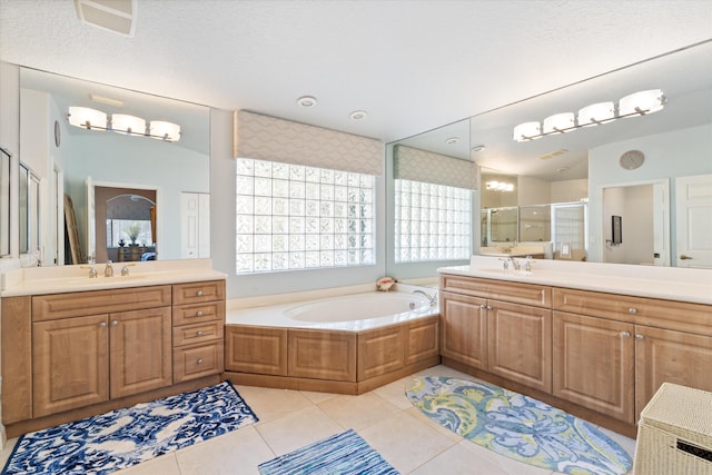 bathroom featuring a bath, a shower stall, a sink, and tile patterned floors